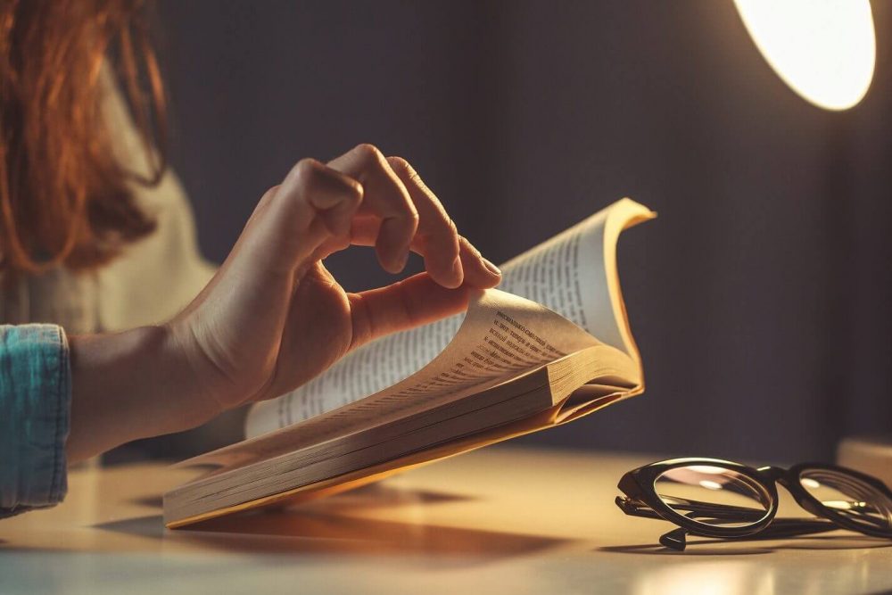 Woman reading book at evening at home