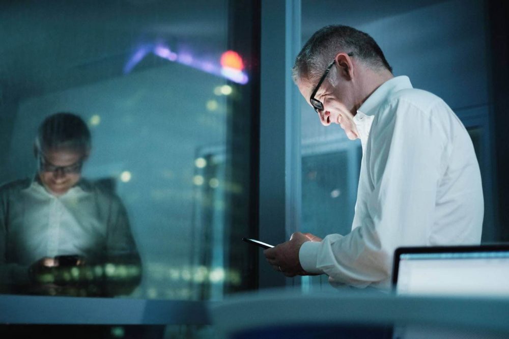 A smiling businessman using his smartphone in the office