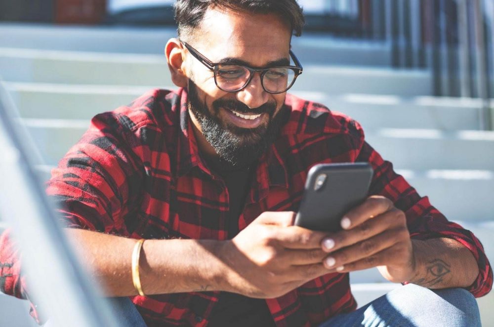 A smiling man looking at his smartphone