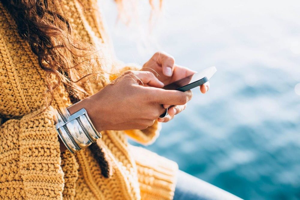 A woman in a yellow sweater writing a message on her phone