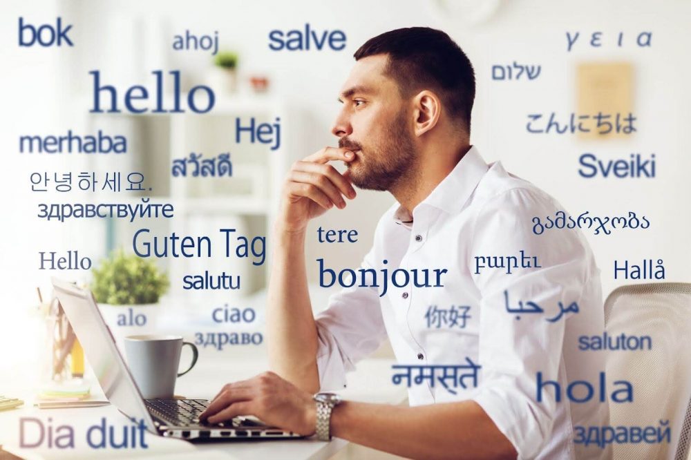 A man working on his laptop surrounded by greetings in multiple languages